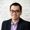 Headshot of Thi Vo standing in front of a white board with equations on it.